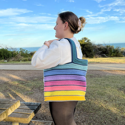 Person carrying a bright coloured crochet tote bag at the beach