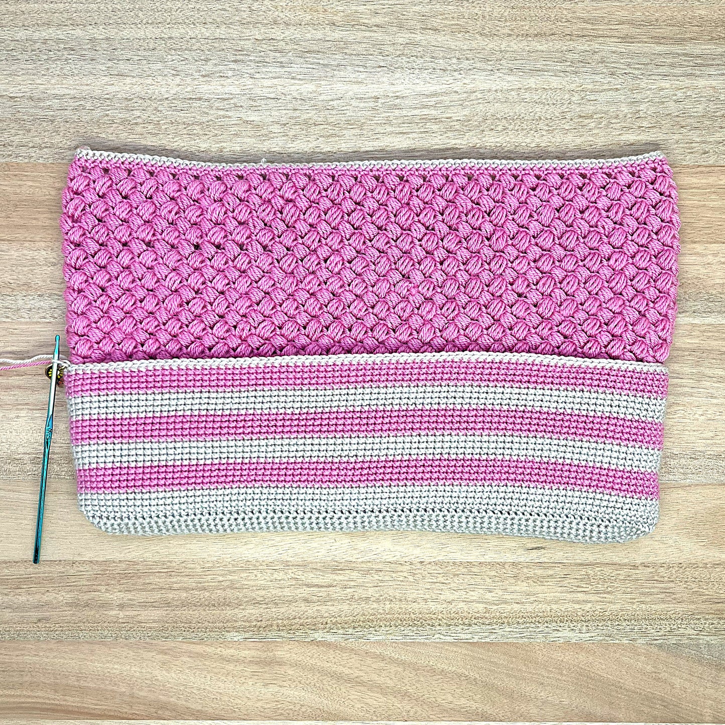 Pink crochet lined pouch with a white stripe on a wooden surface