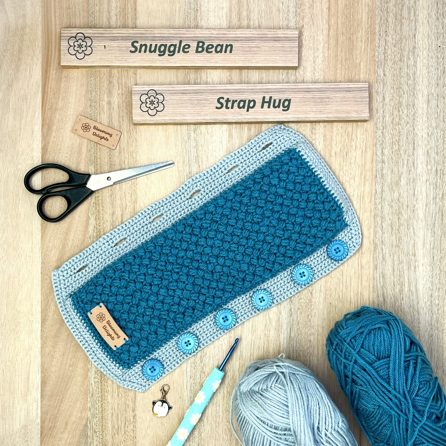Crocheted pouch with blue buttons, yarn, scissors, and wooden labels on a wooden surface