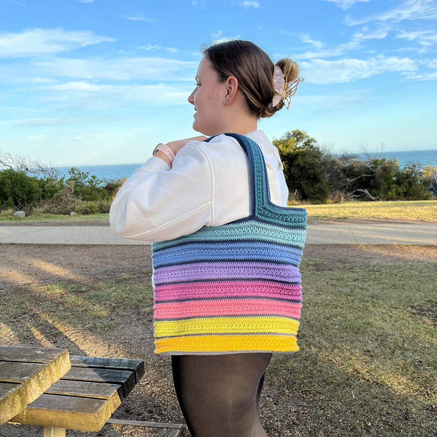Person carrying a bright coloured crochet tote bag at the beach