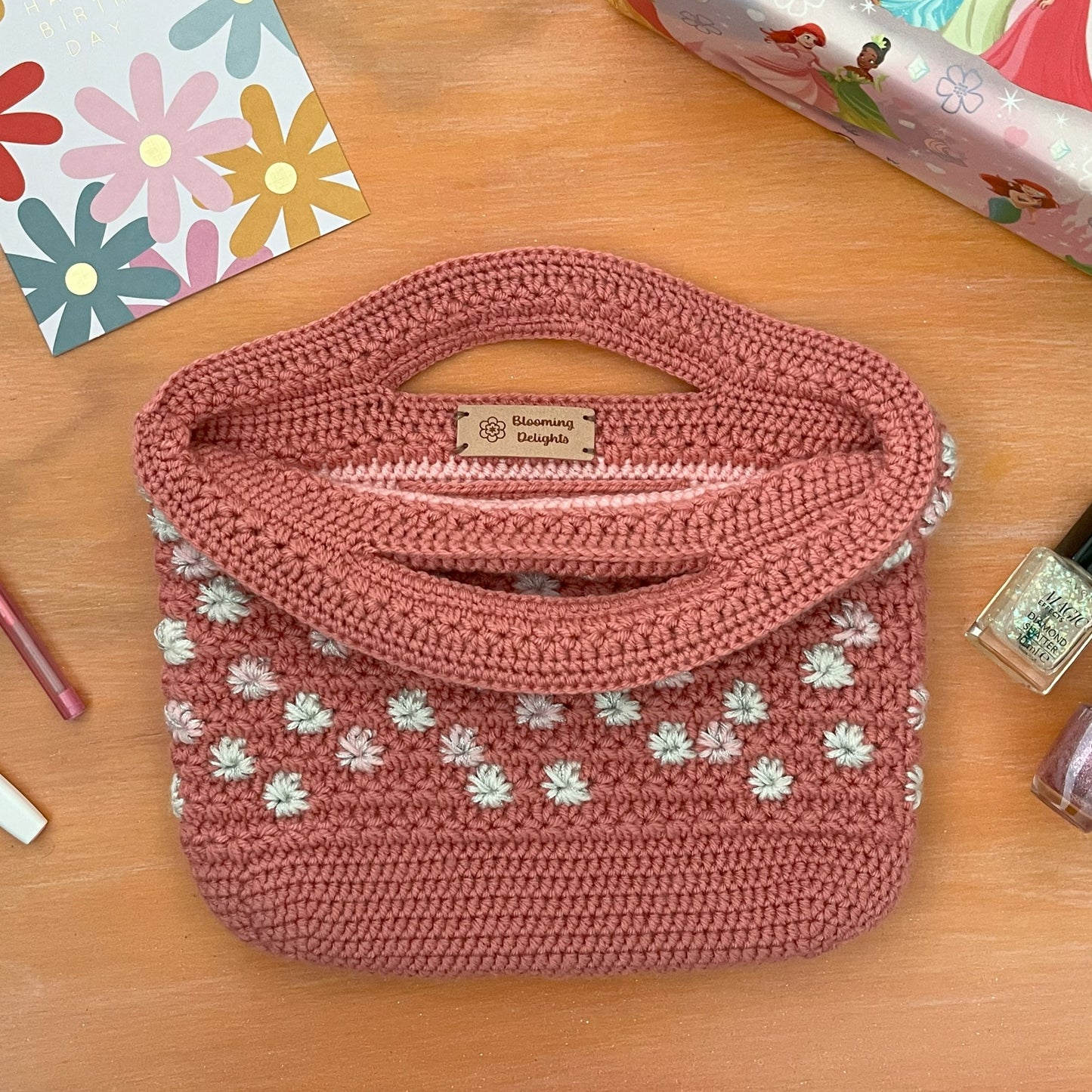 Pink crochet bag with floral patterns on a wooden surface