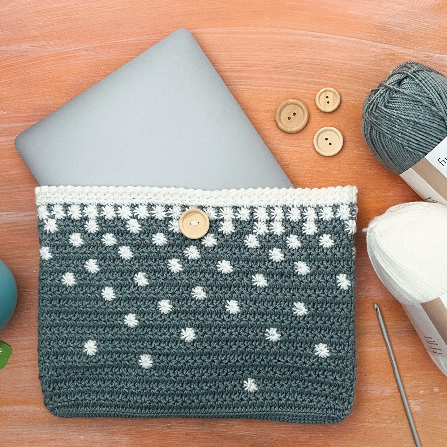 Crocheted pouch with star pattern on a wooden surface with yarn and buttons.