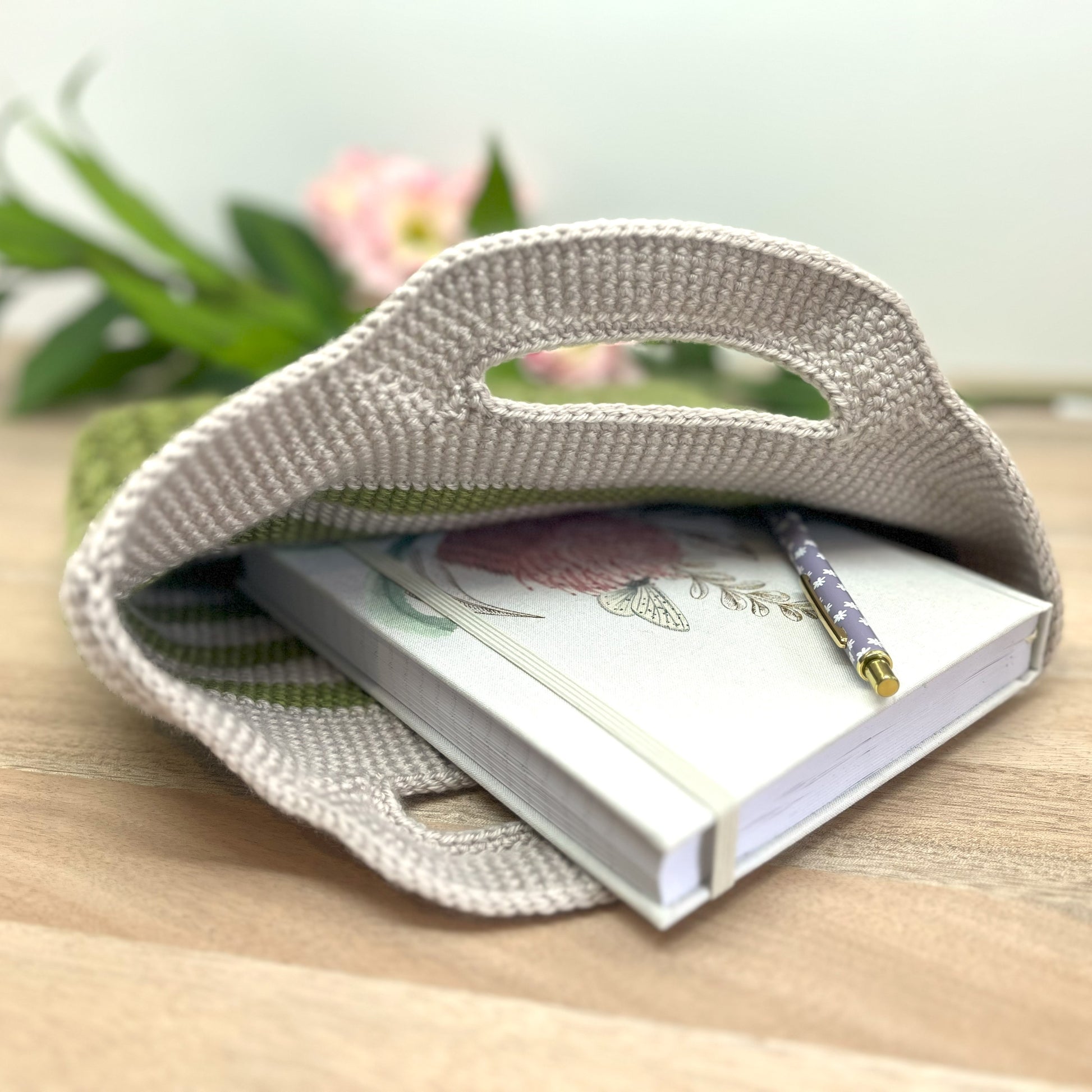 Woven pouch with a notebook and pen on a wooden surface