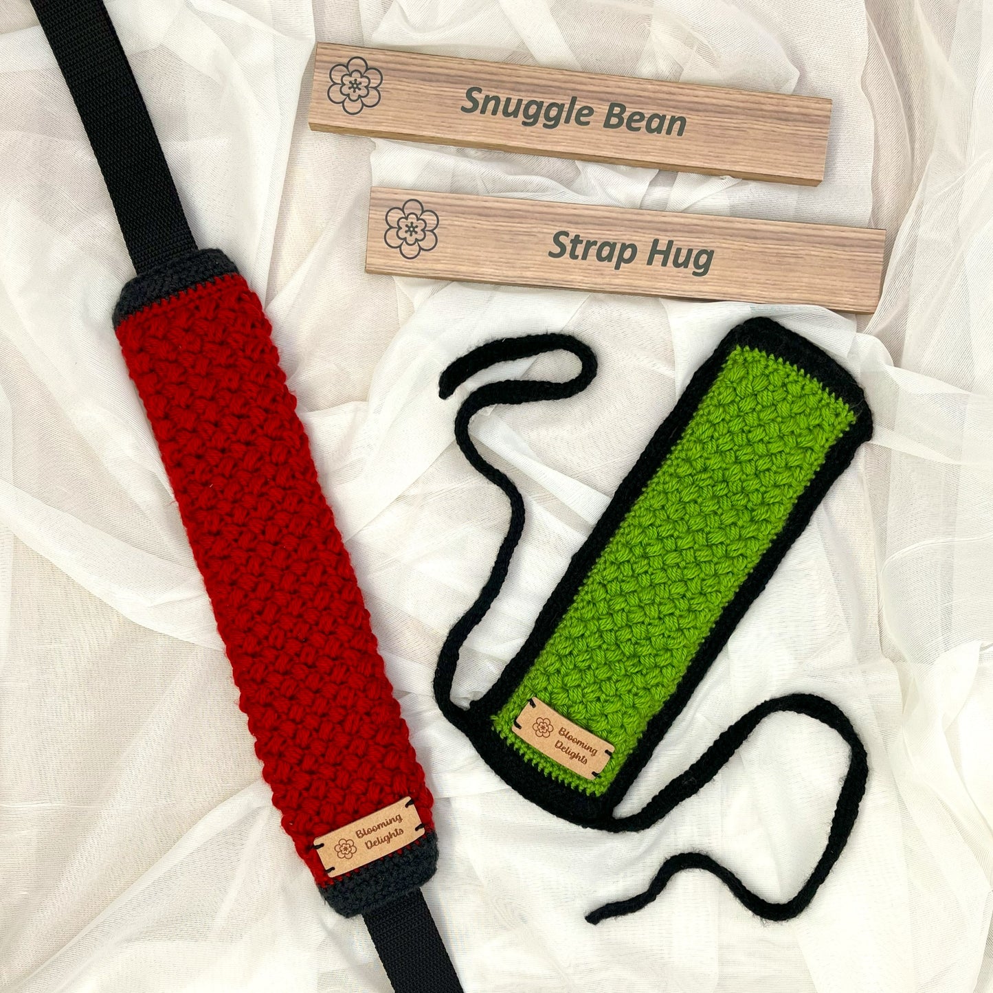 Two knitted strap hug toys, one red and one green, with 'Snuggle Bean' branding on a white fabric background.