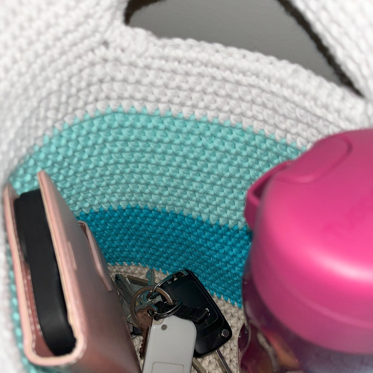 Close-up of a bag with a wallet, keys, and an apple inside.